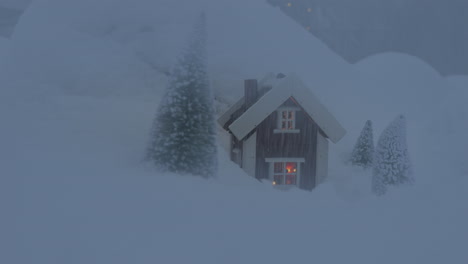 escena de cuento de hadas: cabaña en miniatura en una nieve con pinos que la rodean