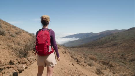 A-young-woman,-a-tourist,-admires-a-beautiful-mountain-valley-bathed-in-clouds