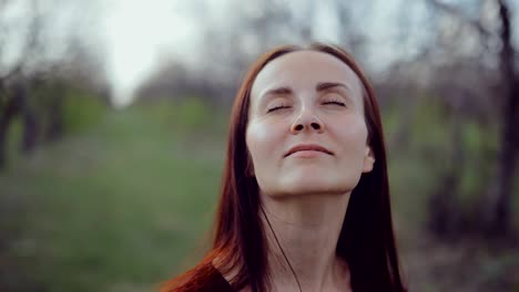 joven se relaja en la naturaleza, se para con los ojos cerrados. movimiento circular de la cámara.