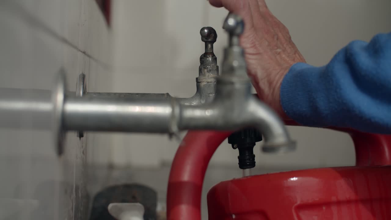 4K at 24fps - Woman filling a red watering can - Home mood