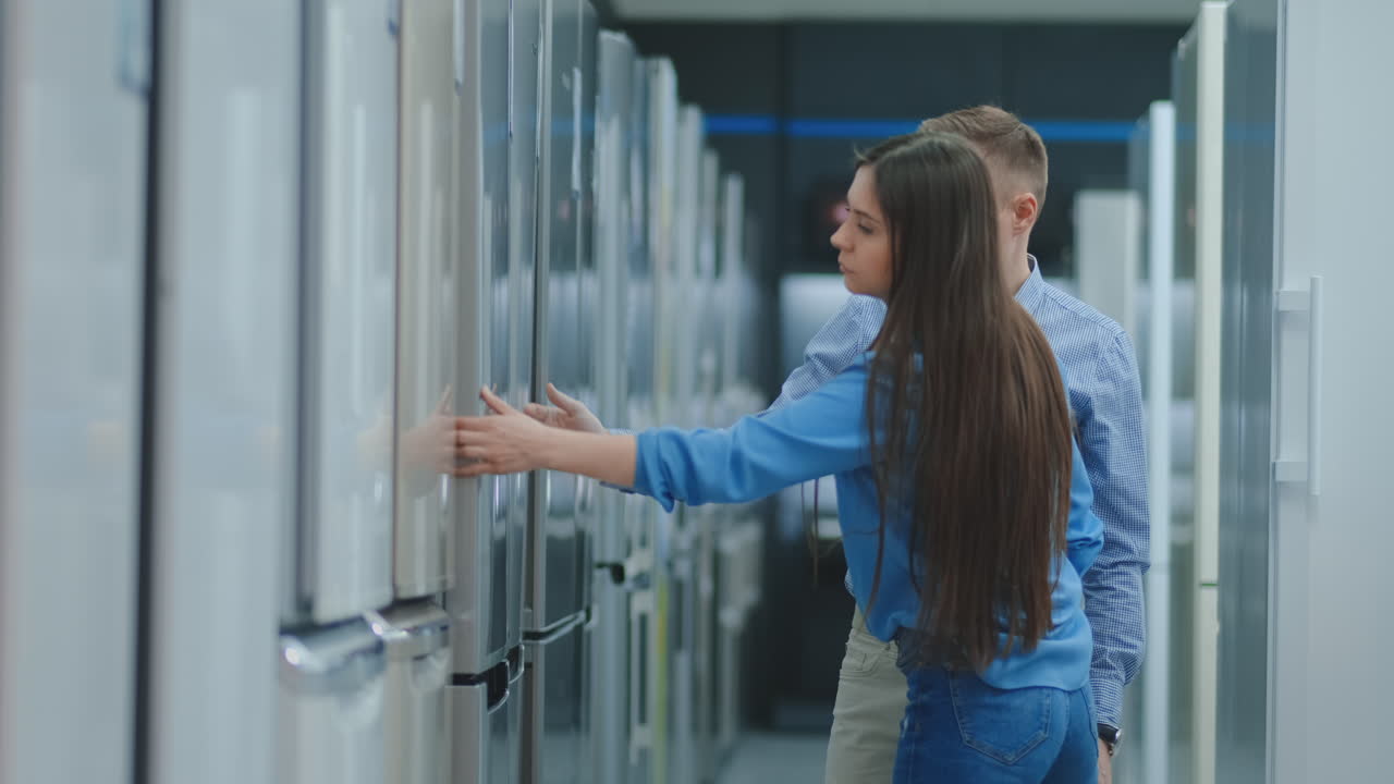 un hombre y una mujer eligen un refrigerador para comprar en una casa nueva