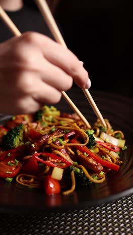 woman eating asian noodles with chopsticks