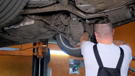 a mechanic performing maintenance on the underside of a car in a garage