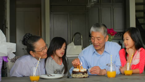 front view of old senior asian grandfather lightning birthday cake candles in a comfortable home 4k