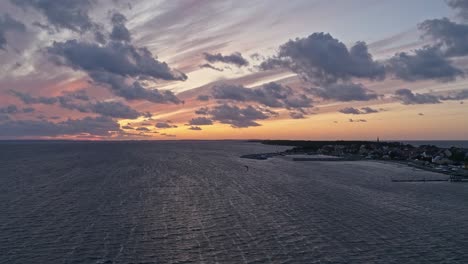 Silueta-De-Un-Hombre-En-Una-Tabla-De-Cometas-En-El-Mar-Al-Atardecer,-Vista-Aérea