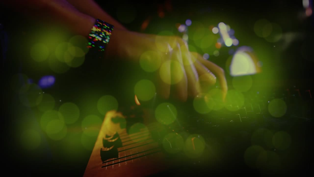 Musicista che preme un tasto della tastiera e suona accordi dal vivo, regolando le manopole del mixer mentre il bokeh verde pulsa.