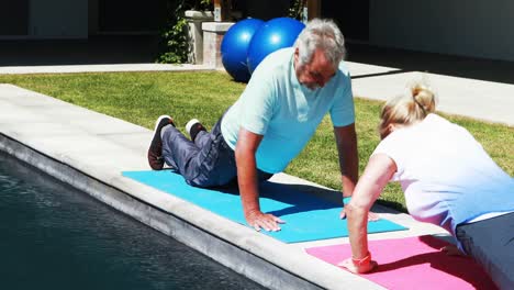 pareja de alto nivel haciendo flexiones cerca de la piscina