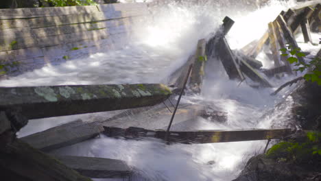 rushing water rapids flowing down log chute and crashing into damaged wooden beams 4k prores