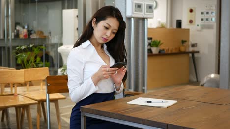 young professional using her phone at a coworking cafe
