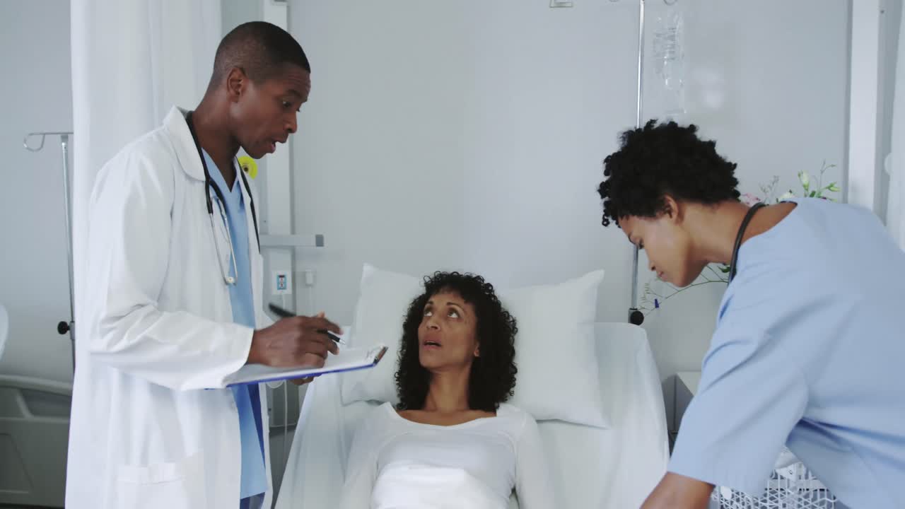Front view of African american doctors examining female patient in the ward at hospital