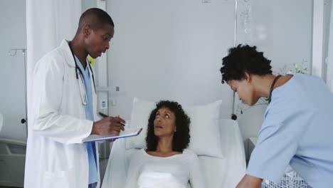 Front-view-of-African-american-doctors-examining-female-patient-in-the-ward-at-hospital