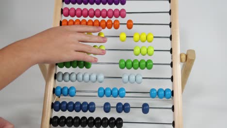 hands manipulating beads on a colorful abacus