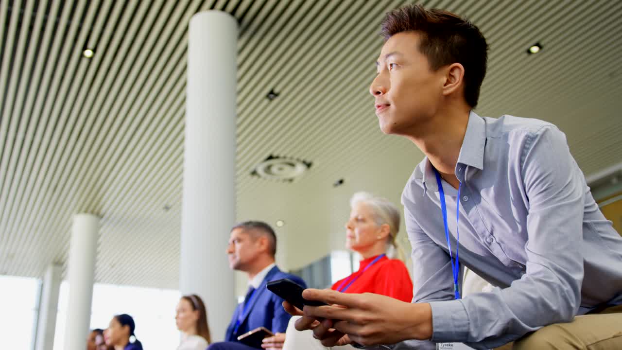 비즈니스 세미나 4k에서 휴대폰을 사용하는 아시아 사업가