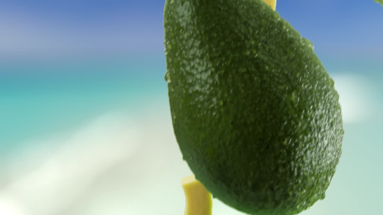 aguacate con rebanadas cayendo en el fondo de la playa