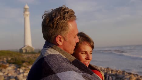 couple embracing by the sea near a lighthouse