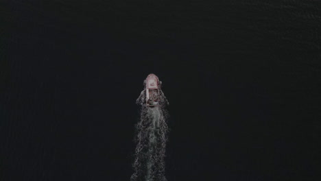 single fishing vessel heading out to sea, overhead drone shot