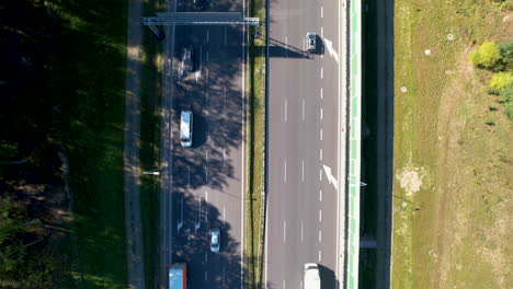 Top-down-aerial-over-a-fast-traffic-road-with-3-lanes-in-each-direction---personal-cars-and-trucks-moving-in-two-directions---modern-road-with-safe-infrastructure