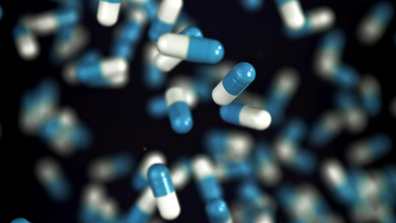 Capsule farmaceutiche blu e bianche che cadono al rallentatore