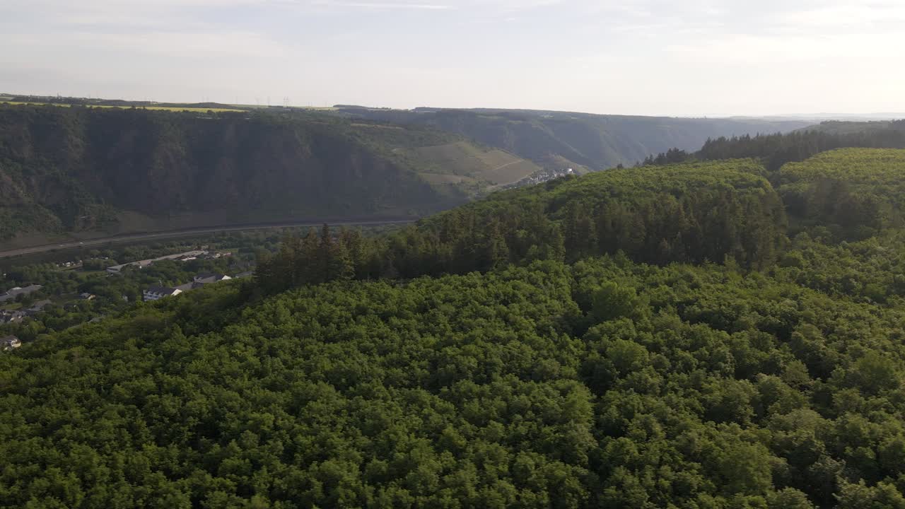 광활한 숲과 산맥 뒤에서 코헴 마을을 드러내는 공중 돌리 샷