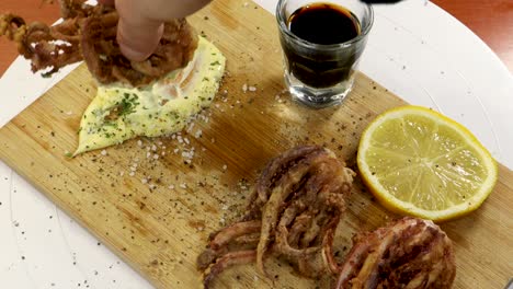 Dipping-fried-squid-into-homemade-aioli-with-lemon-side-dish-and-a-glass-of-soy-sauce