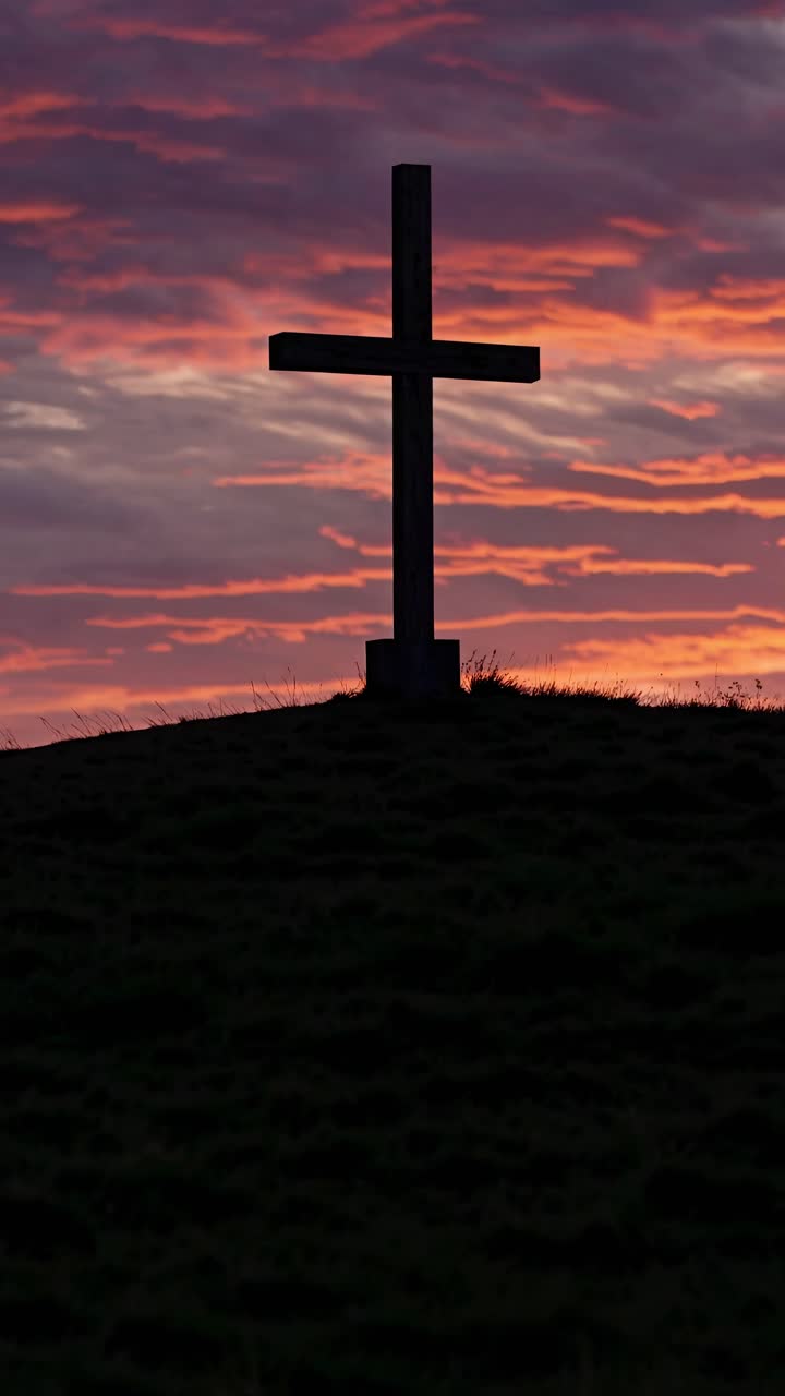 Silhouette di una croce su una collina al tramonto, ripresa da un angolo basso