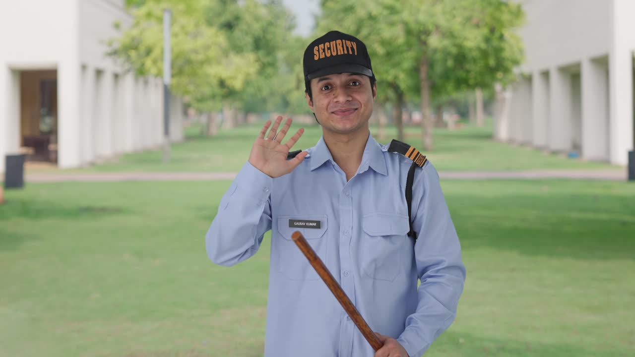 Happy Indian security guard waving Hi to the camera