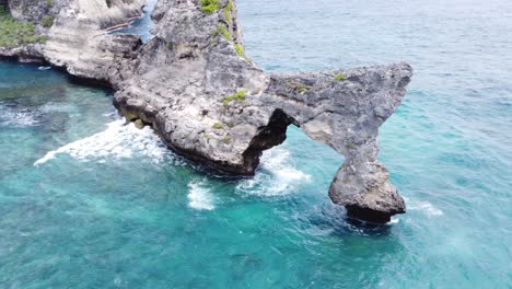 Die-Tosenden-Wellen-Des-Indischen-Ozeans-Zerschmettern-Einen-Natürlichen-Felsbogen-Am-Strand-Von-Atuh,-Nusa-Penida