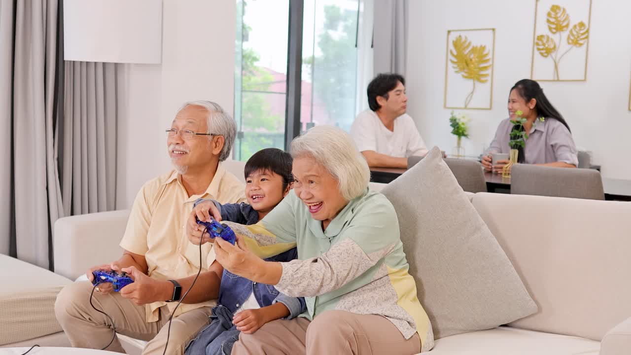 モダンなリビングルームで、高齢の夫婦と幼い男の子が楽しそうに一緒にビデオゲームをしている。