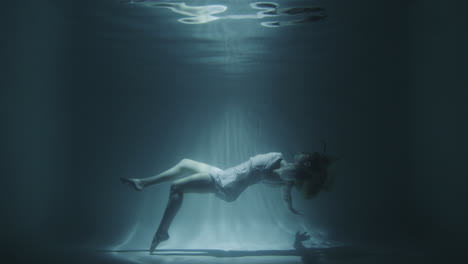 girl in a white dress swims underwater