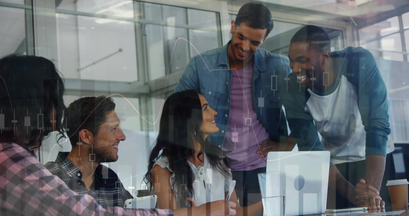 Seated woman speaking and gesturing at monitor, team leaning in reviewing overlaid financial charts