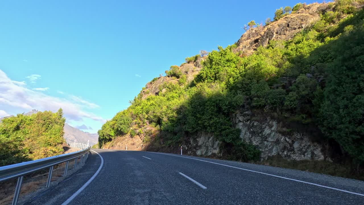 POV drive on winding mountain road, lush greenery, bright daylight, smooth camera movement, clear sky