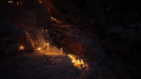 candles illuminate rocky path in dark cave during evening hours