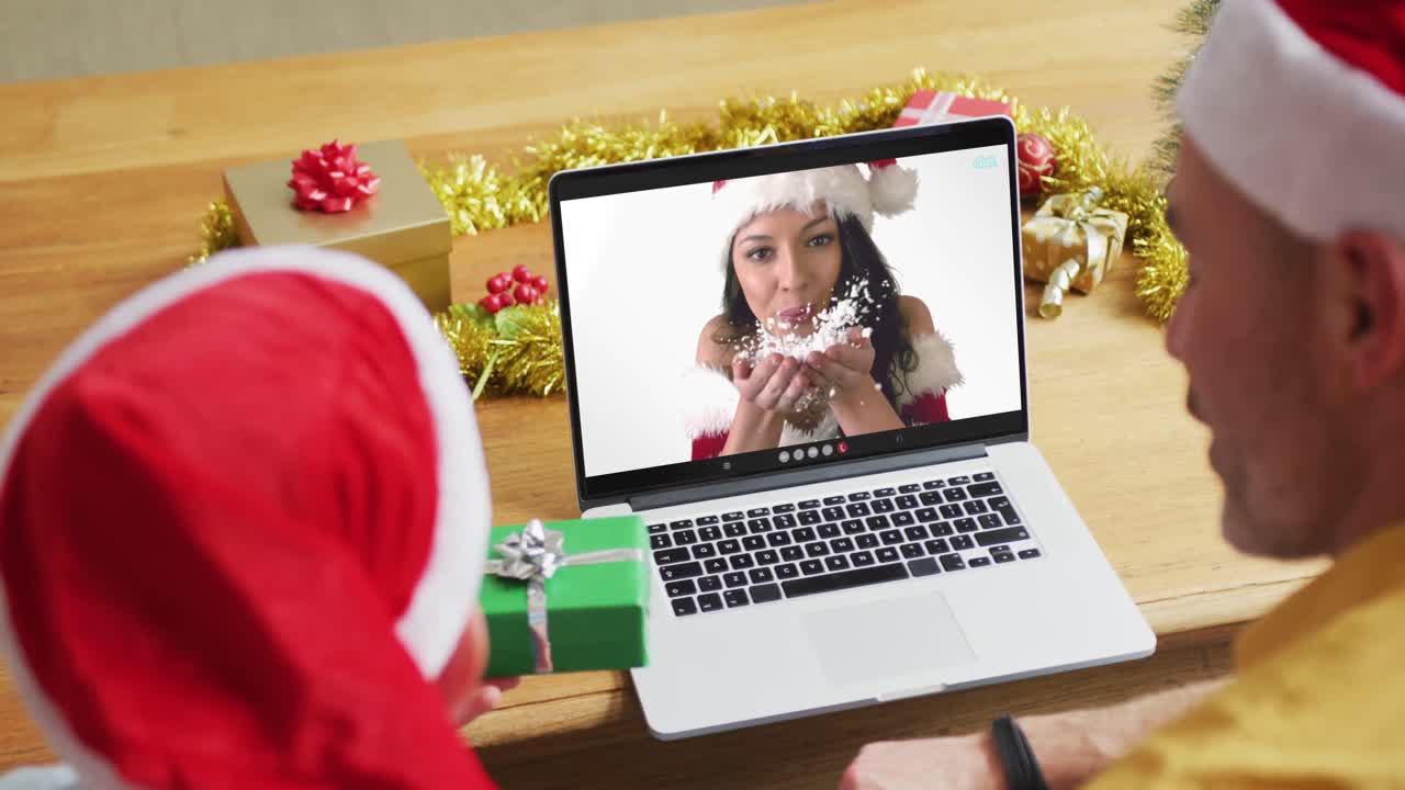 padre y hijo caucásicos con sombreros de santa usando una computadora portátil para una videollamada de navidad con una mujer en la pantalla