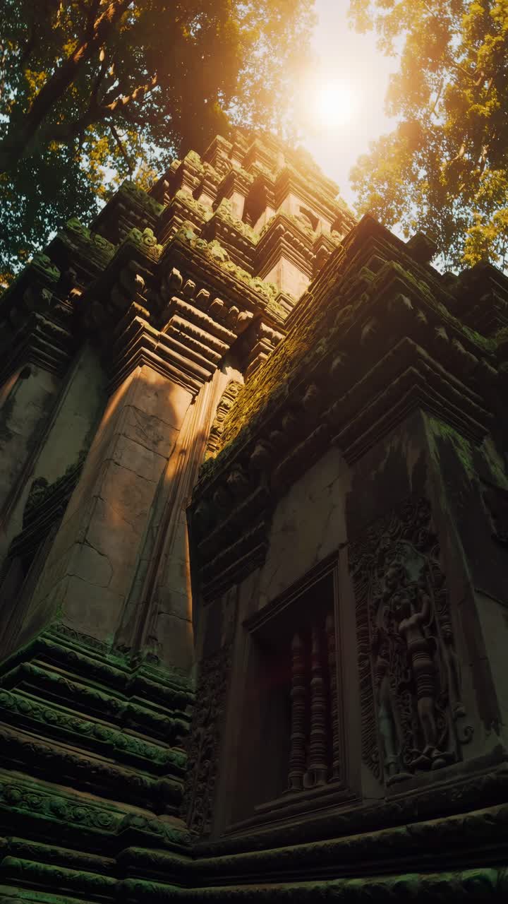 Low-angle video shot of ancient temple ruins surrounded by lush trees, capturing the intricate