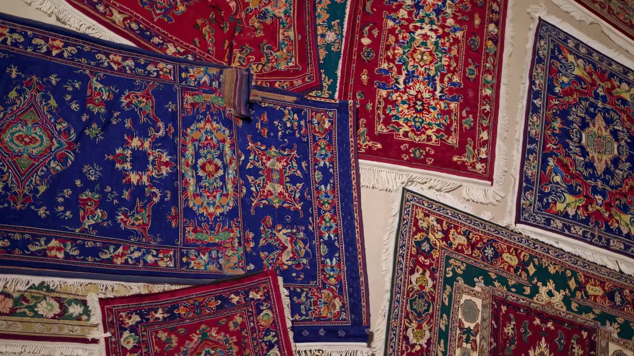 Colorful Persian carpets hanging on white wall, showcasing intricate geometric designs and vibrant textile artistry from traditional Middle Eastern weaving techniques