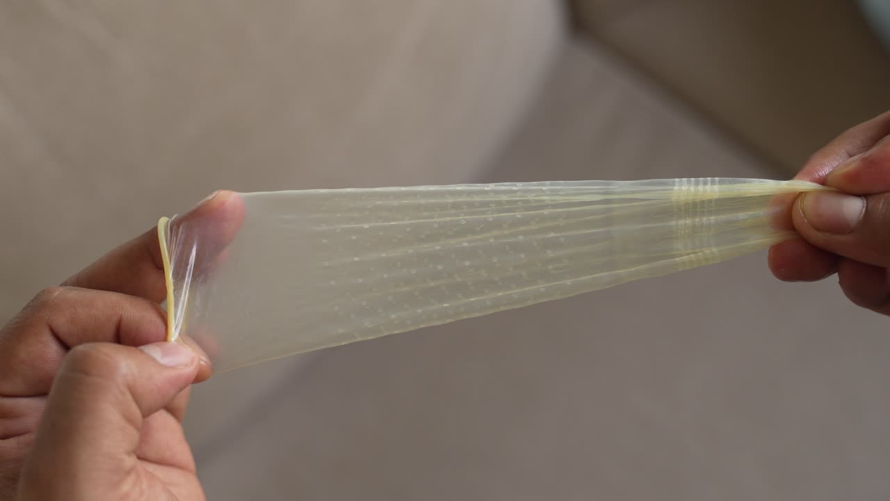 Ein gepunktetes Kondom dehnen, um seine Flexibilität zu zeigen