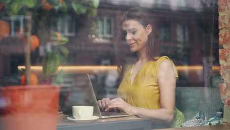 mujer trabajando en una computadora portátil en un café