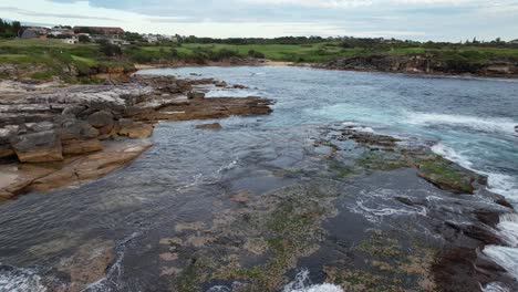 Waves-Splashing-On-The-Rocks-At-Little-Bay-Beach-In-New-South-Wales,-Australia---Drone-Shot