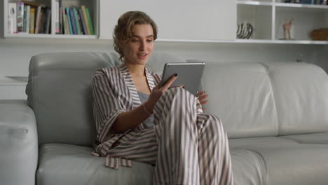 cheerful girl making video call at home interior. smiling lady waving at tablet