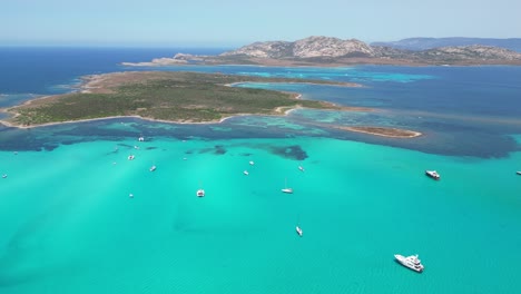 boats at turquoise blue sea during summer in la pelosa, sardinia, italy - 4k drone aerial