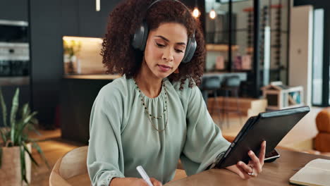 woman with headphones working on tablet at home