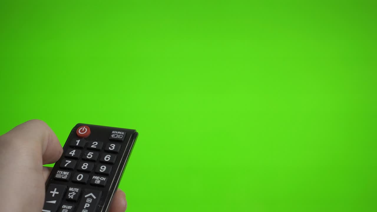 리모컨을 들고 있는 남성의 손이 tv를 녹색 스크린 위로 켜고 광고를 찍습니다.