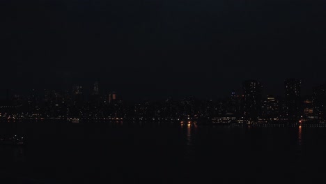 Drohnenschwenk-Im-Uhrzeigersinn-über-Die-Skyline-Von-Manhattan,-New-York,-Von-Der-Anderen-Seite-Des-East-River-Bei-Dunklem-Sonnenuntergang-Mit-Booten-In-4K