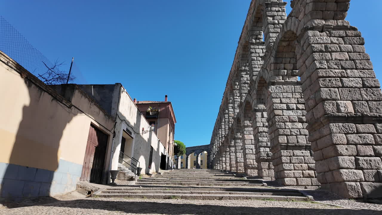 Lento movimento in avanti verso l'acquedotto di Segovia con prospettiva stradale, archi in pietra e dintorni urbani in Spagna