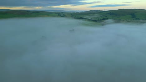Rising-above-misty-fog-bank-revealing-distant-hills-at-sunrise