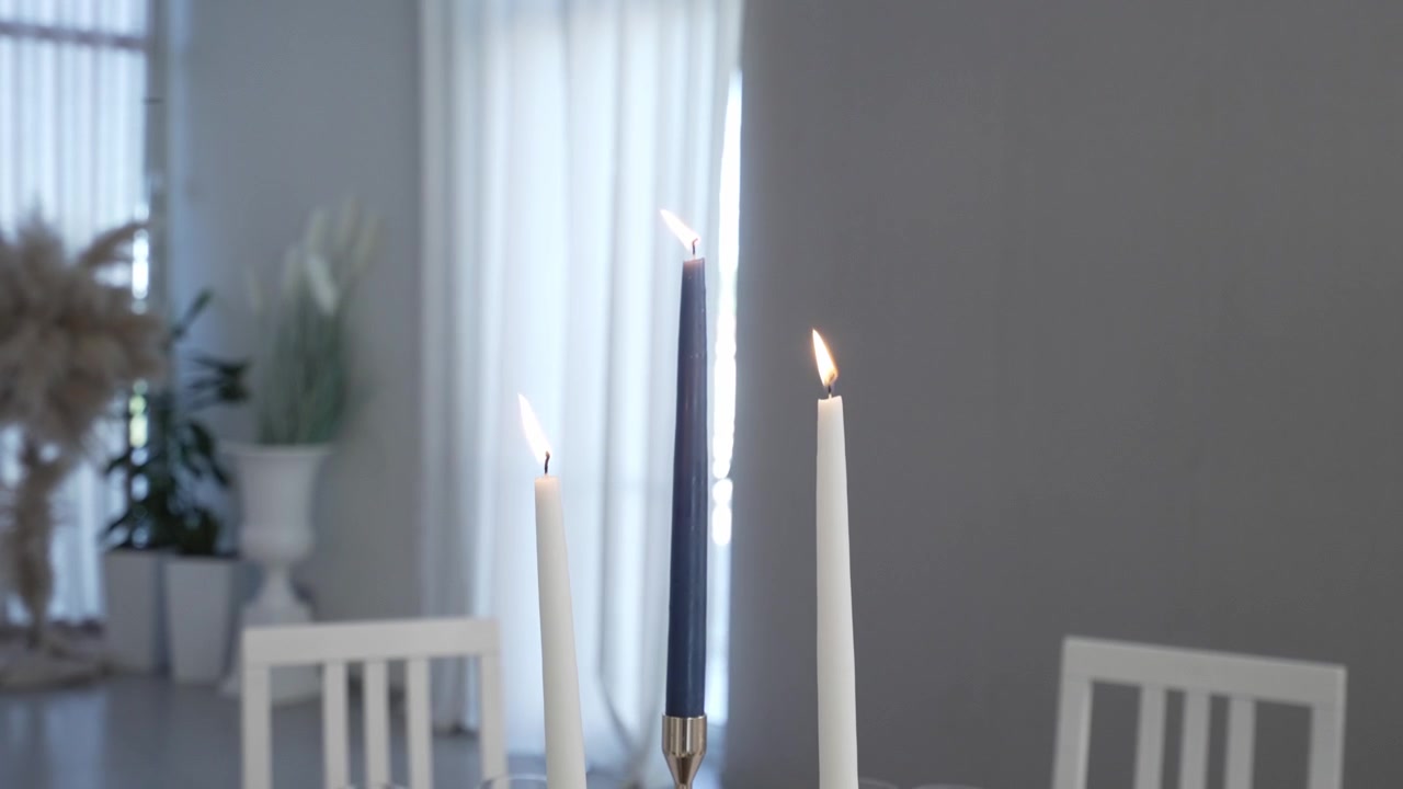 Tre candele accese su un elegante tavolo da pranzo, creando un'atmosfera serena e accogliente