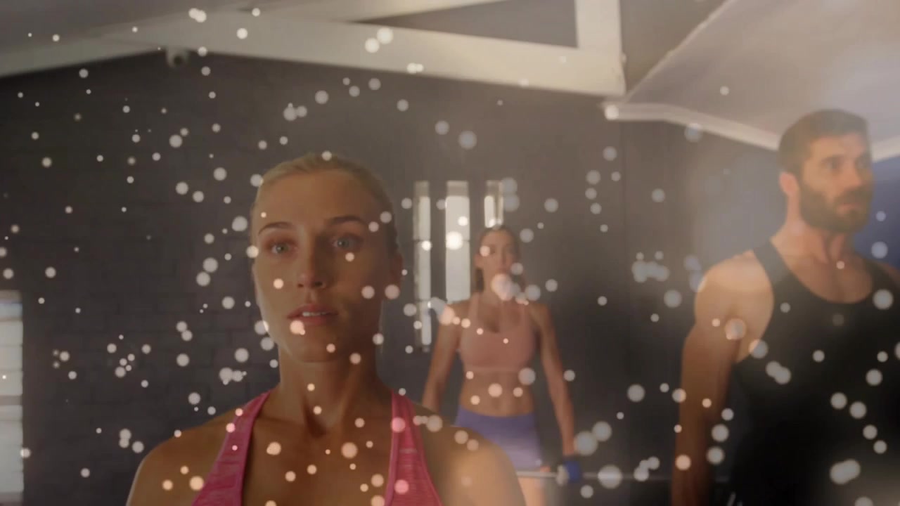 En kvinde starter et løft, kameraet trækker sig tilbage og afslører en duo med bokeh, der viser vægte til fitness.