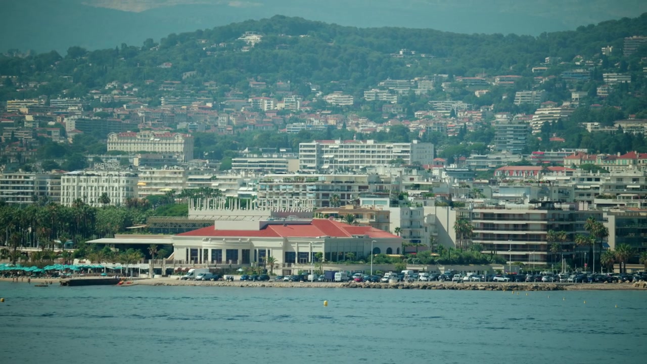 Paesaggio urbano di Cannes con edifici che scendono a cascata dalle colline verso il Mar Mediterraneo e una vivace costa balneare