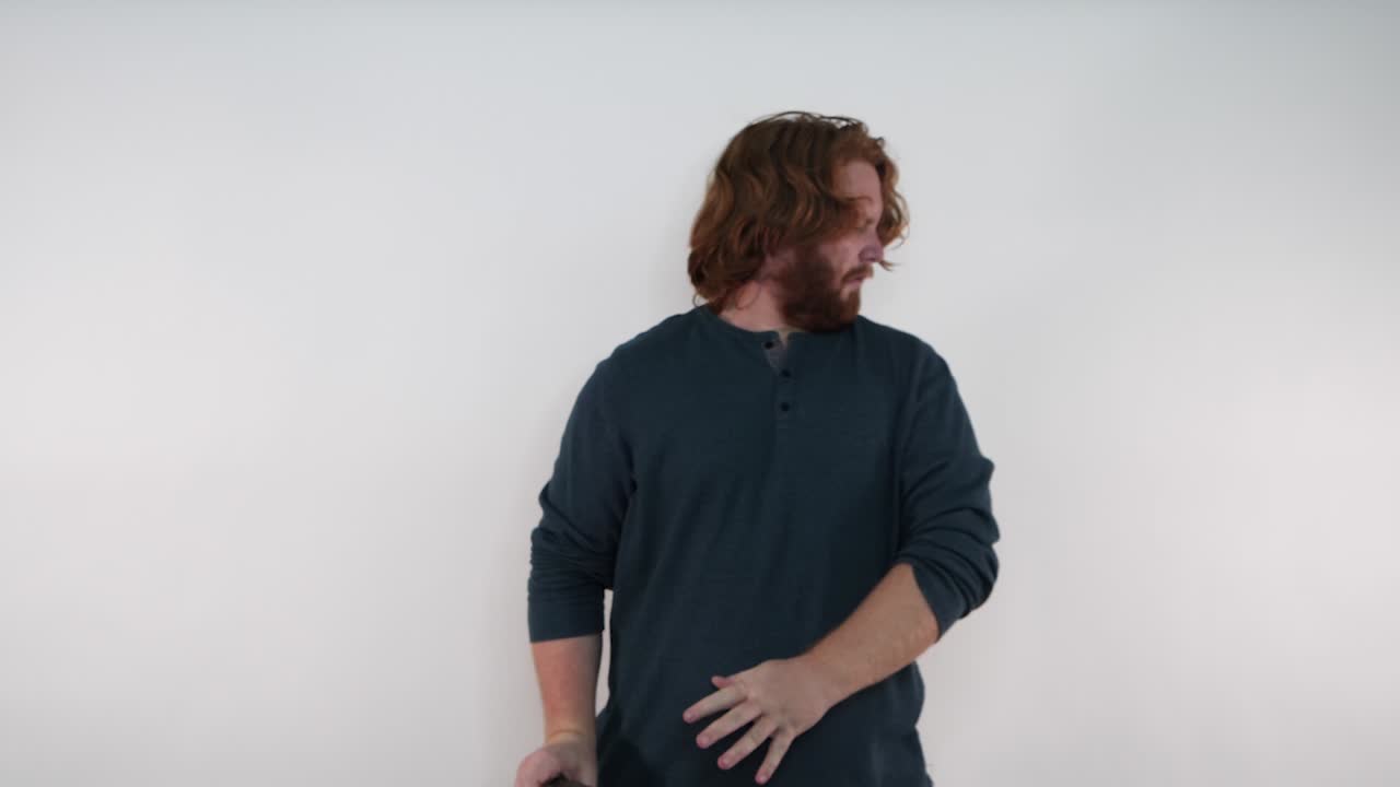 Red haired man smells some laundry and turns in disgust