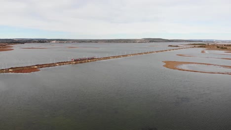 Aerial:-passenger-train-on-a-dam-by-the-sea-in-southern-France-during-winter